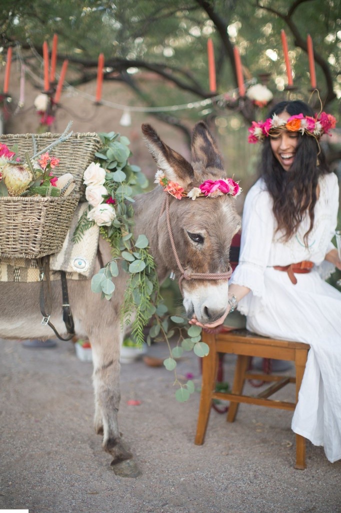 A mini donkey wearing a floral crown beside a woman in a flower crown